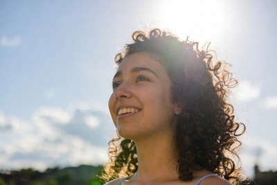 Smiling woman with curly hair in sunlight
