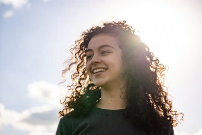 Smiling woman with curly hair outdoors