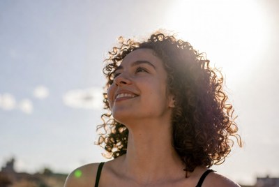 Smiling woman with curly hair looking up