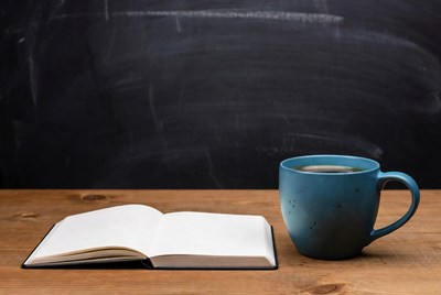 Open notebook and blue mug on table