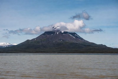 Volcano erupting over lake