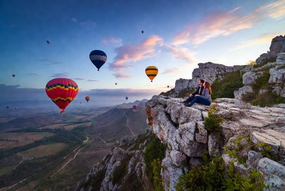 Couple watching hot air balloons from cliff