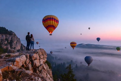 Couple watching hot air balloons from cliff
