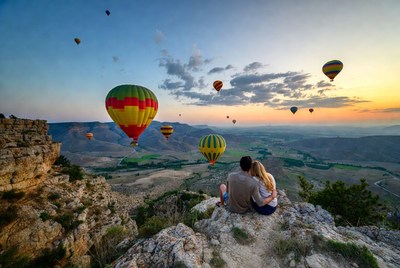 Couple watching hot air balloons from cliff
