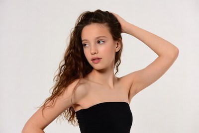 Teen girl with wavy hair hand on head