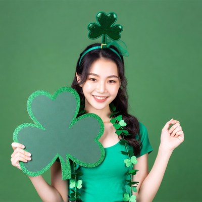 Asian woman holding shamrock St. Patrick's Day