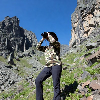 Woman using binoculars in mountains