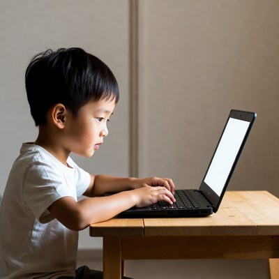 Asian boy typing on laptop