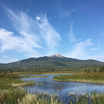 Mountains reflecting in marsh under blue sky