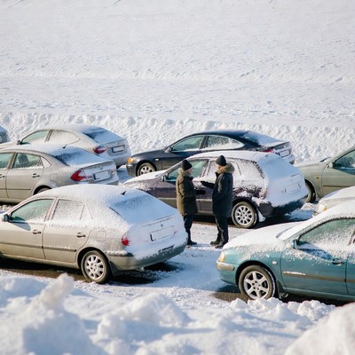 Two people talking by snowy cars