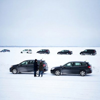 Two men standing by cars on snowy field