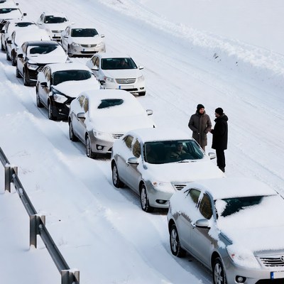 Two people talking beside snowy traffic jam