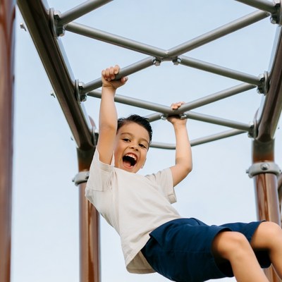 Boy hanging on playground bars