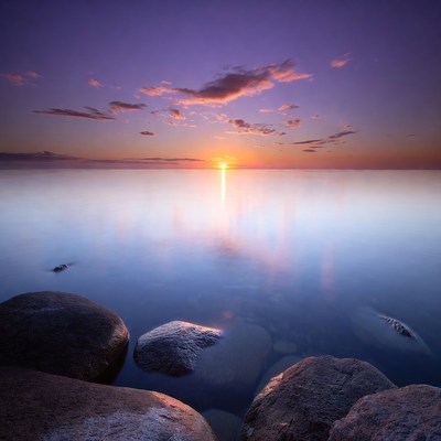 Sunset over calm sea with rocks