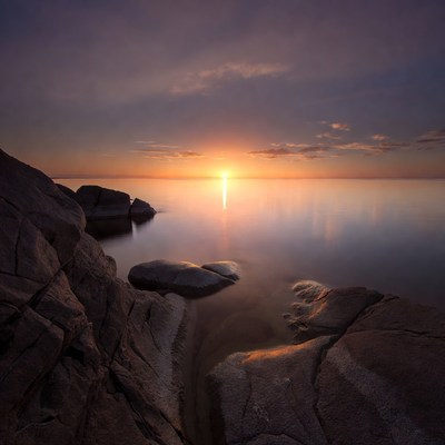Sunset over calm sea with rocks