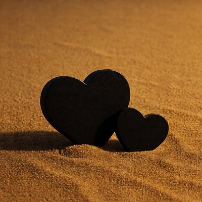 Two black hearts on sand