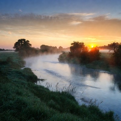 Sunrise over misty river landscape