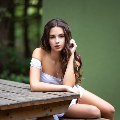 Young woman sitting on wooden bench in forest