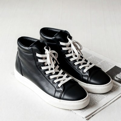 Black leather high-top sneakers on newspaper