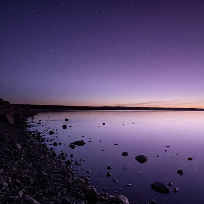 Purple starry sky over rocky lakeshore