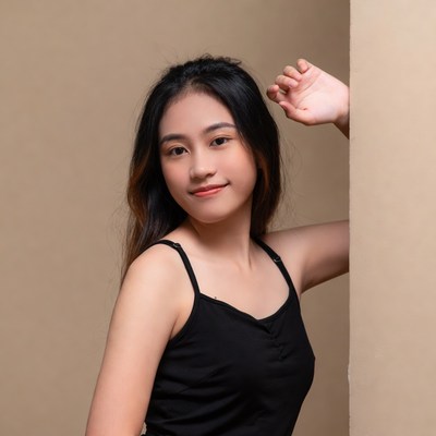 Asian woman waving from behind wall