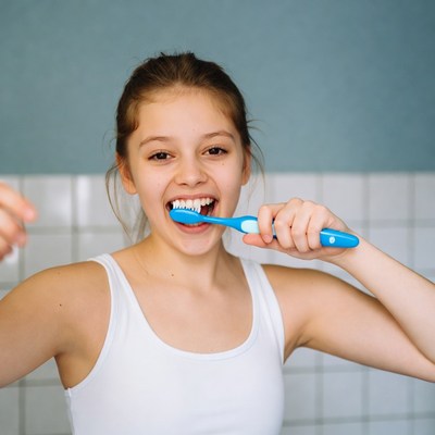 Girl brushing teeth with blue toothbrush