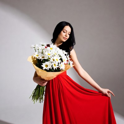 Woman holding white daisies in red dress