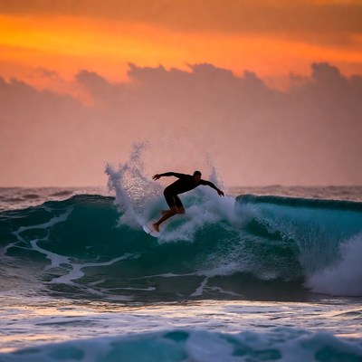 Surfer riding wave at sunset