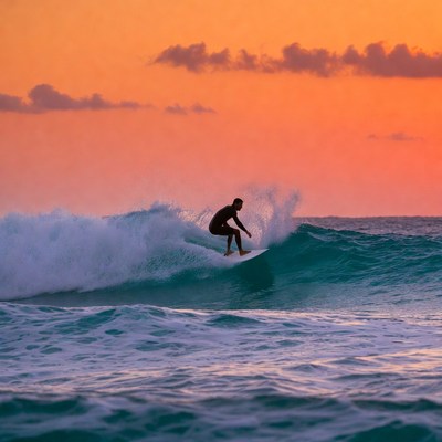 Man surfing on wave at sunset