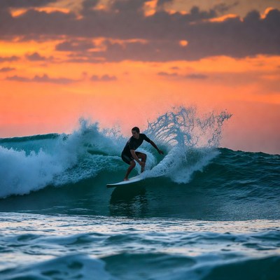 Man surfing on wave at sunset