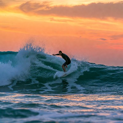 Surfer riding wave at sunset