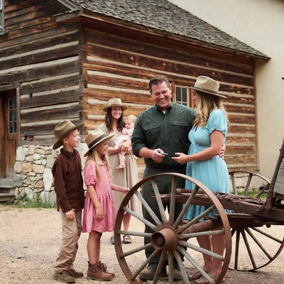 Family with baby near log cabin wagon