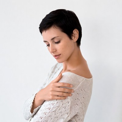 Woman with short black hair in off-shoulder sweater