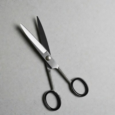 Open silver scissors on gray surface