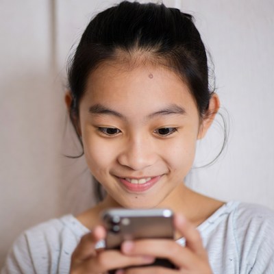 Asian girl smiling using smartphone