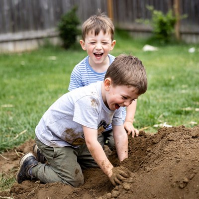 Boys digging in backyard dirt pile