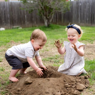 Toddlers playing in backyard dirt pile