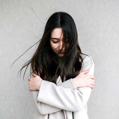 Asian woman hugging herself in coat