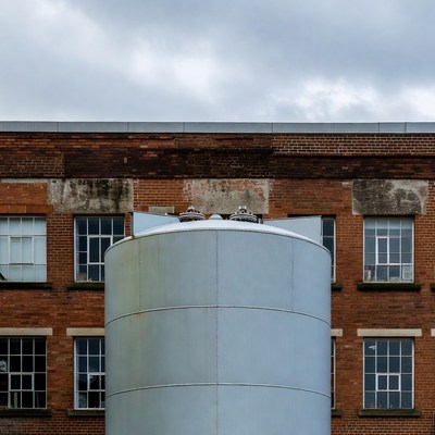 Silver Silo Against Brick Factory