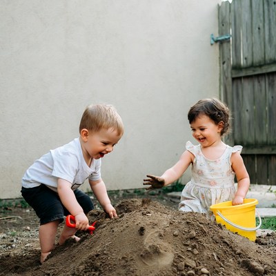 Boy and girl playing in sand pile