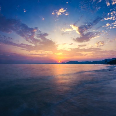 Sunset over calm ocean with mountains