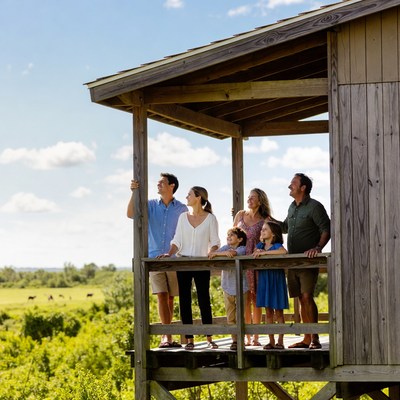 Family standing on wooden deck overlooking fields