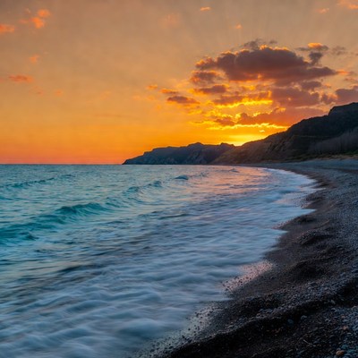 Sunset over pebbly beach and cliffs