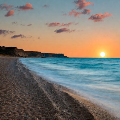 Sunset over pebbly beach and cliffs