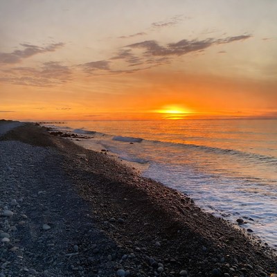 Sunset over pebbled beach