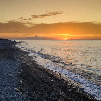 Sunset over pebbled beach