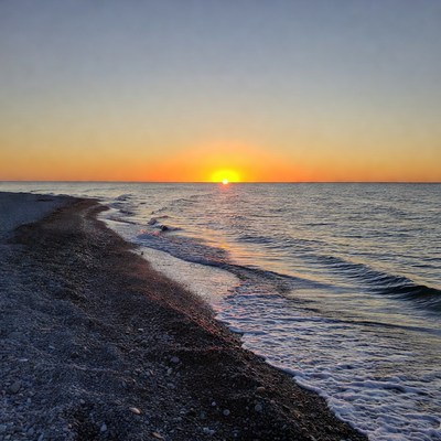 Sunset over pebbly beach