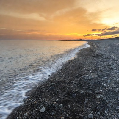 Sunset over pebbled beach