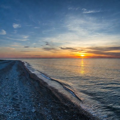 Sunset over pebbled beach