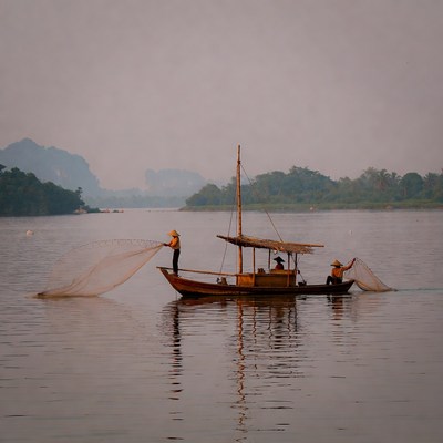 Asian fishermen casting nets from boat
